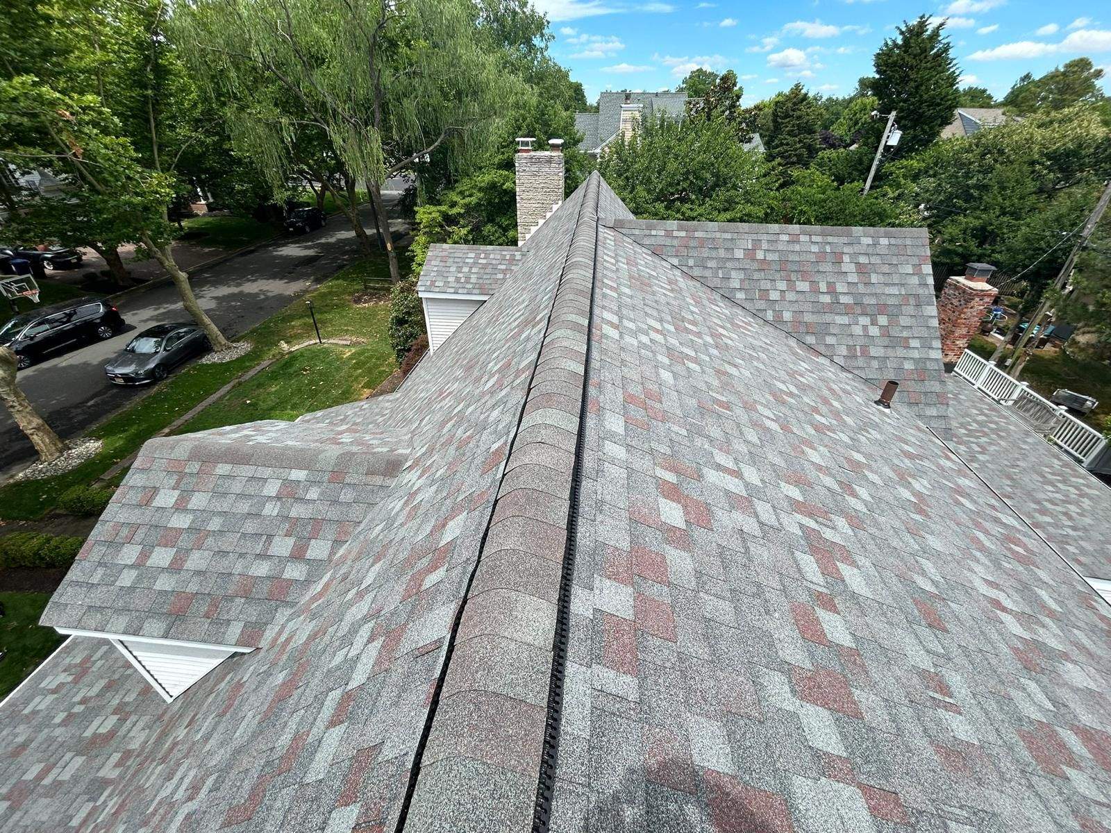 Roof view showcasing asphalt shingles installed by Costello Roofing, highlighting quality workmanship in Linwood, NJ, surrounded by residential area and greenery.